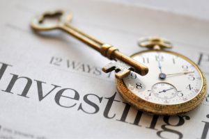 Investing newspaper with key and old watch