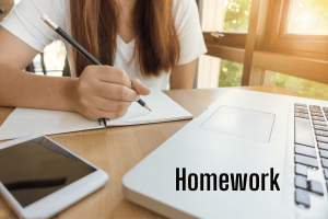 Girl in front of computer with pencil and paper. Homework text on laptop